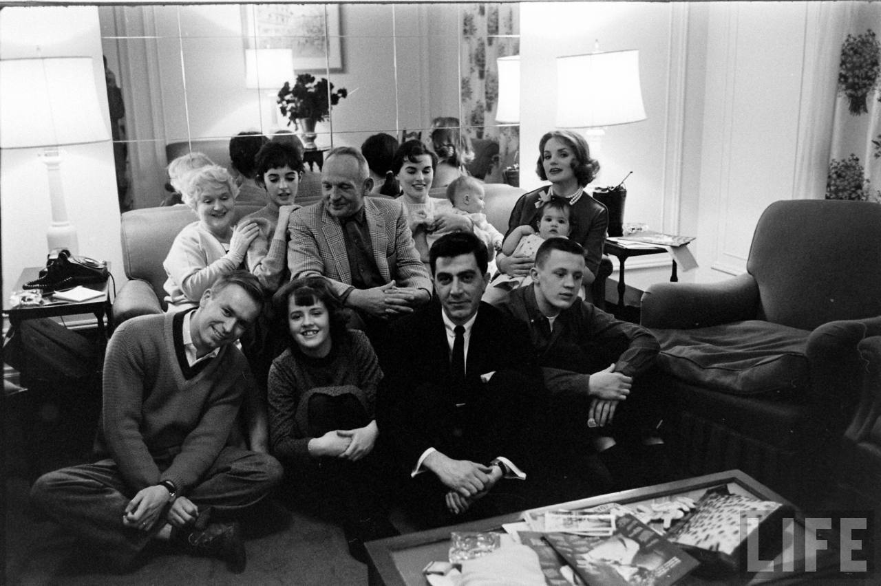"My mom is in the upper far right, she is holding me on her lap. I was about 10 months old. Millie is second from top left between my grandparents. Dad is sitting down in the front wearing a dark suit"