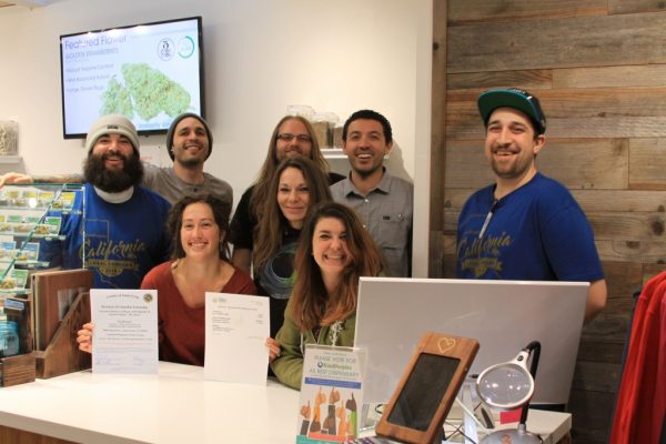 KindPeoples staff pase in front of some of the first state licenses to sell cannabis in history.