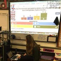Photo of teacher sharing data on screen in classroom