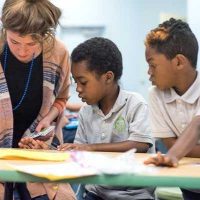 Photo of two students looking on as teacher explains ratios with cards