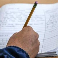 Photo close up of notebook with person making notes in pencil
