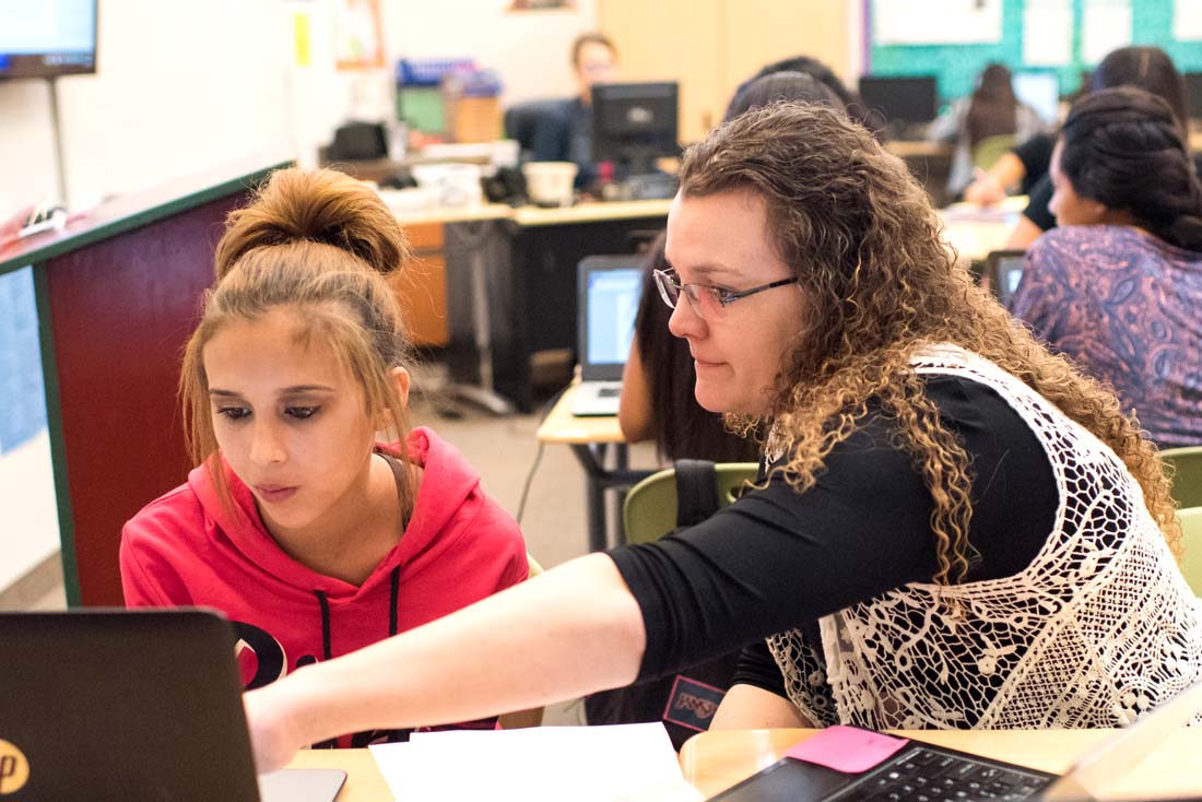 teacher and student look at a laptop screen teacher and student look at a laptop screen