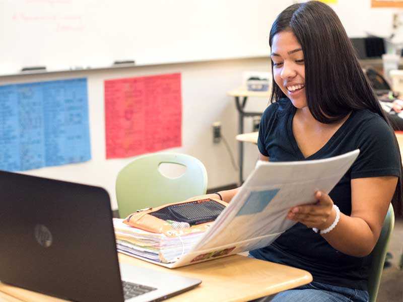 Photo of Lindsay student opening binder in front of laptop