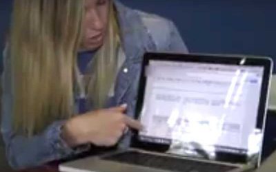 Photo of student explaining learning management system on her laptop to audience