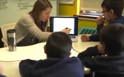 Photo of teacher explaining content from laptop to a group of students