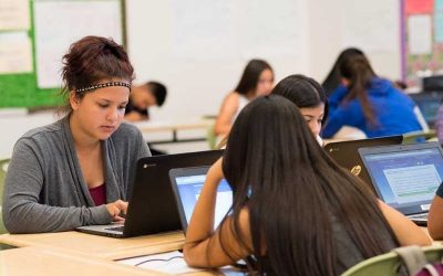 Photo of several students working at laptops at classroom table