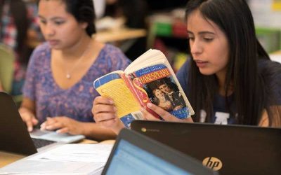 Photo of student reading Shakespeare with another student in background