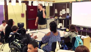 Photo of teacher instructing seated groups of students