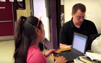 Photo of teacher and student working one on one with laptops