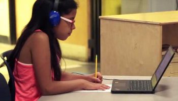 Photo of student working on paper and looking at laptop screen