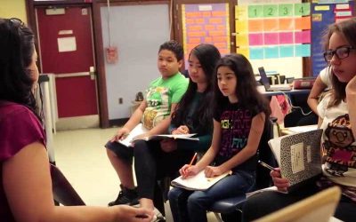 Photo of teacher working with small group of seated students