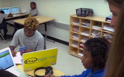 Photo of teacher in classroom where students are working in small groups and on devices