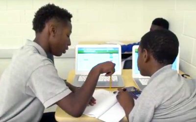 Photo of two students working together with notebooks and laptop computers