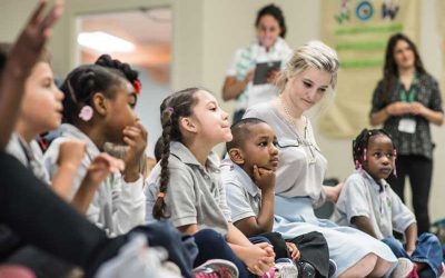Photos of students seated with teacher and other teachers standing in background