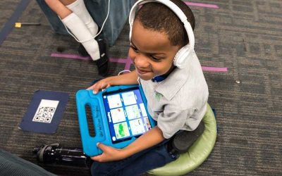 Photo of student seated and working on tablet with headphones