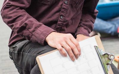 Photo closeup of clipboard containing paper schedule with teacher in background