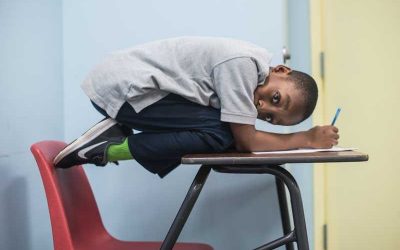 Photo of student crouched ontop of desk