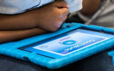Photo closeup of tablet screen reading "Good Work" with student in background