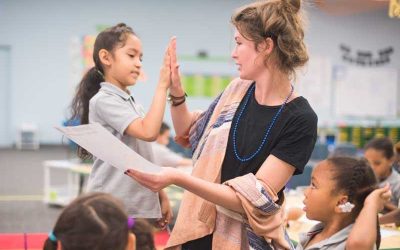 Photo of student and teacher giving each other high-five celebrating sucess
