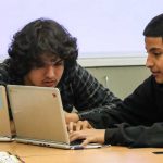 Photo of two students working together in front of laptop