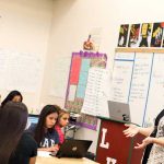 Photo of teacher speaking to a group of students in classroom