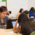 Photo of several students working at laptops at classroom table