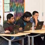 Photo of group of students working on laptops at classroom table