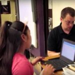 Photo of teacher and student working one on one with laptops