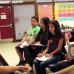 Photo of teacher working with small group of seated students