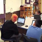 Photo of seated students looking at projector in front of classroom