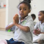Photo closeup of student with hands together at heart center for mindfulness