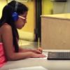 Photo of student working on paper and looking at laptop screen