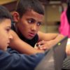 Photo of two students working together on laptops and in conversation
