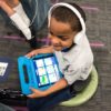Photo of student seated and working on tablet with headphones