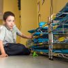 Photo of student seated in front of device storage cart filled with tablet devices