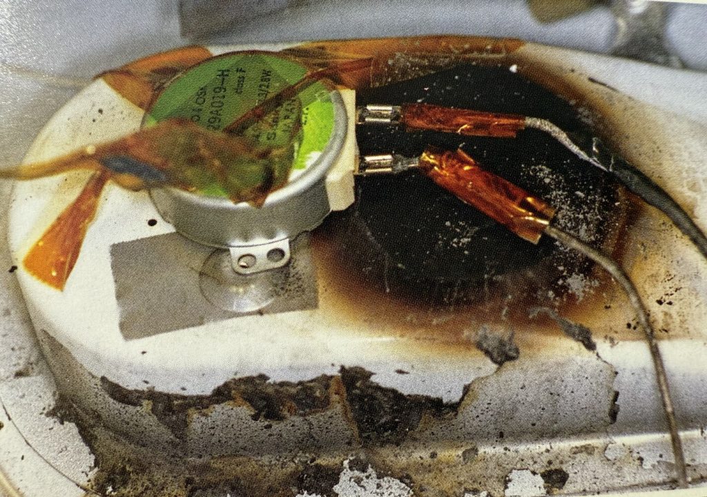 Corroded and dirty industrial equipment with green label. Burn marks near electical connectors