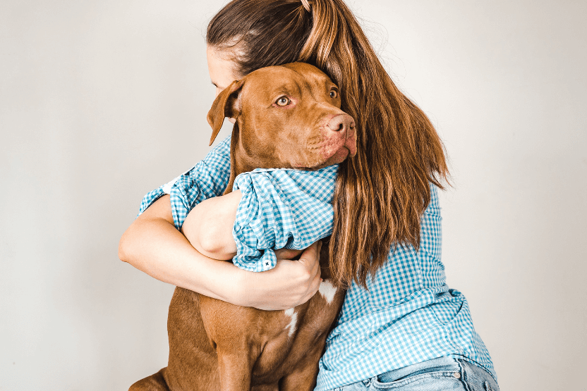 Woman hugging a brownish-red dog - How to Hug Your Dog on National Hug Your Hound Day