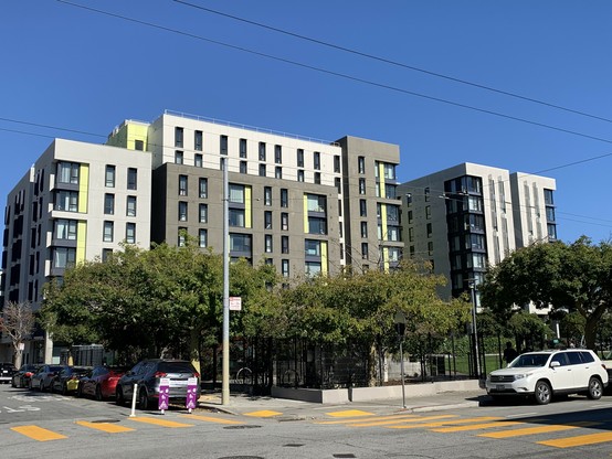 City park (In Chan Kaajal) with 8 story gray and white building behind it