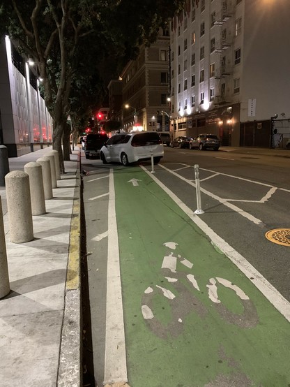 Flex post-separated bike lane blocked completely by an SUV. There is a line of SUVs in the lane in front of that one.