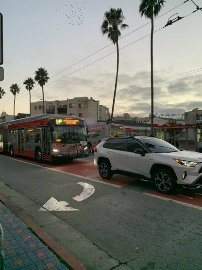 A picture facing the other direction. The same white SUV is visible as in the first picture, and a 14R Mission Rapid bus to Ferry Plaza is behind it.