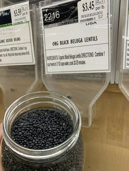glass jar filled with tiny black lentils next to a bulk bin of organic black beluga lentils $3.45 per pound