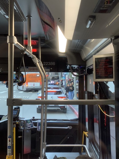 View of Waymo stopped at a red curb through the front of a bus.