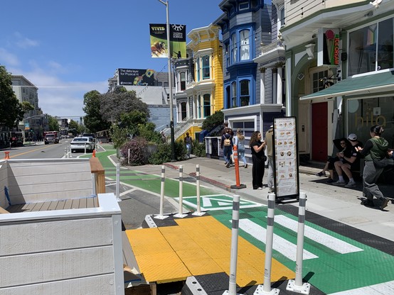 Parklet’s bike lane crossing. The bike lane goes up and over a green-painted ramp with white stripes indicating a pedestrian crossing