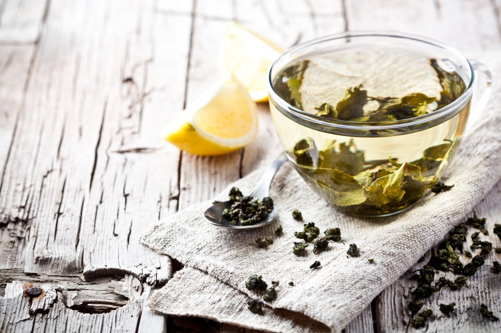 cup of green tea and lemon on rustic wooden table