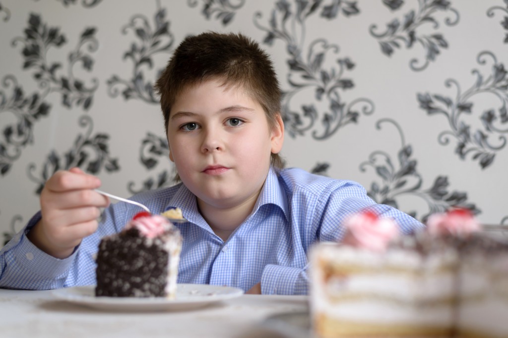 fat kid eating cake in a kitchen
