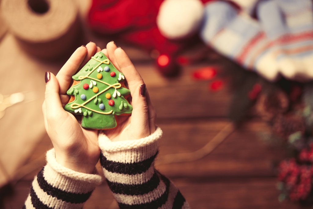 Woman wrapping a christmas cookie on wooden background, photo from high point of view