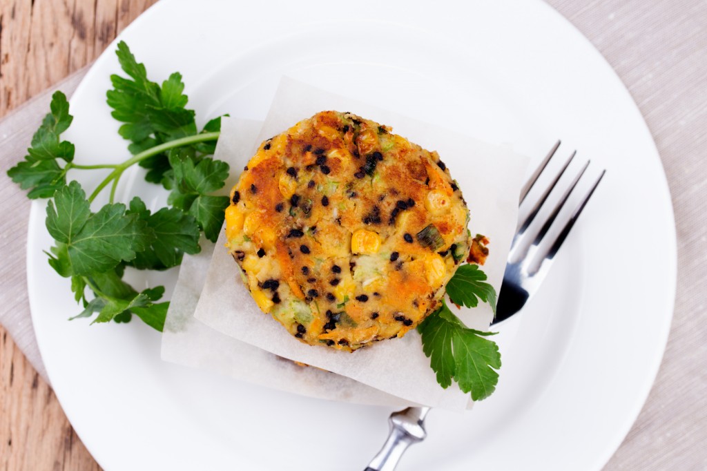Vegetarian patties or burger made with chickpeas on white plate. Rustic wooden background.