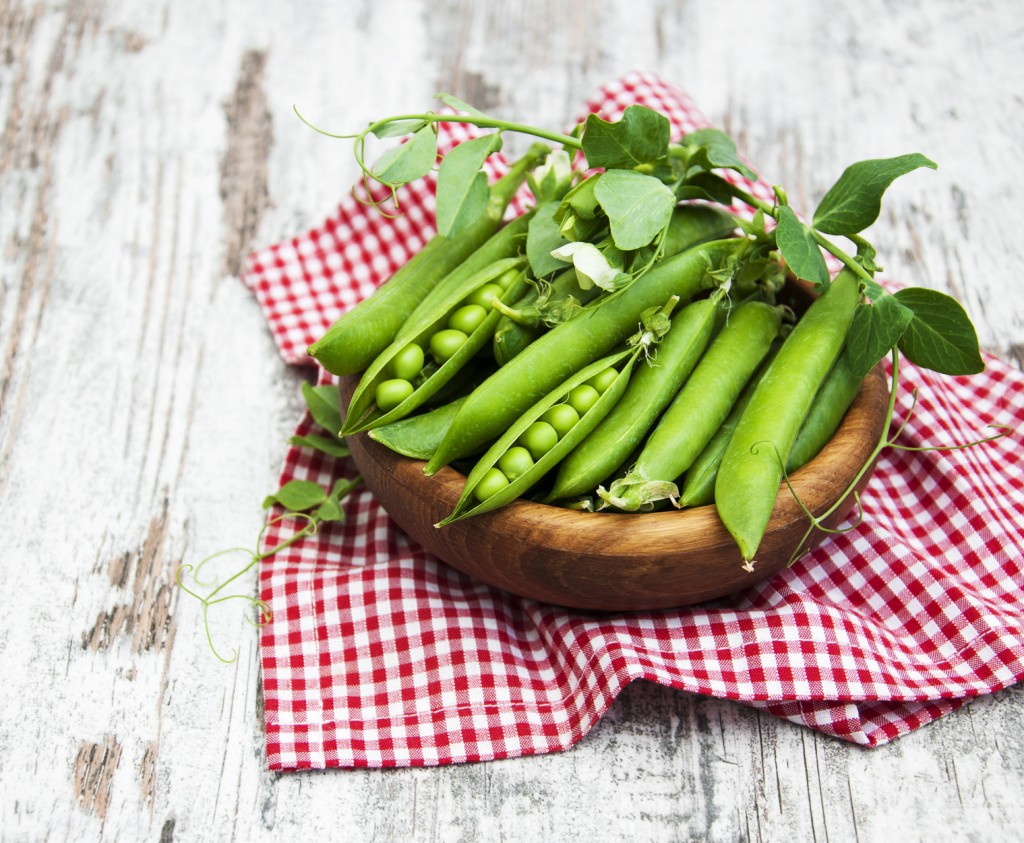 Bowl with fresh peas on a old wooden background