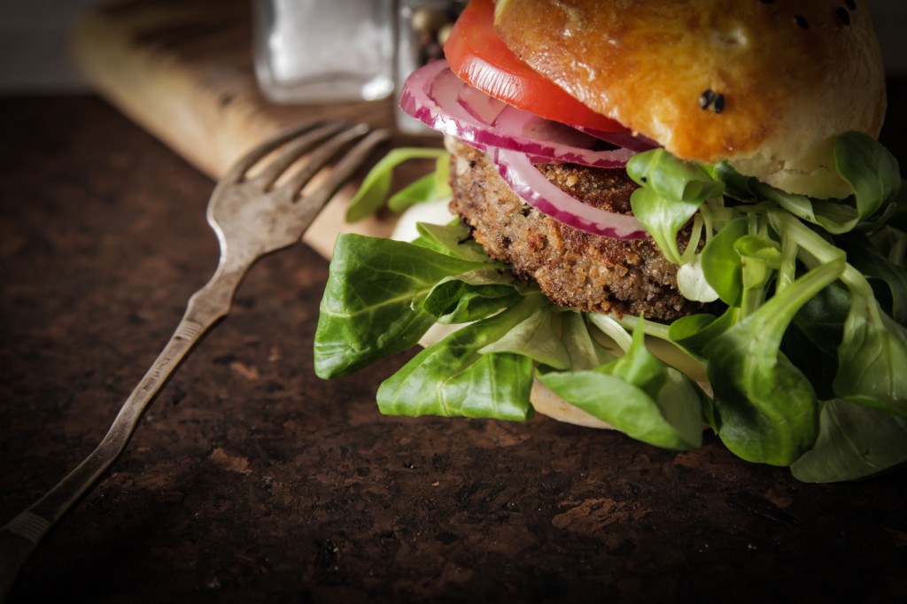 homemade veggie burger in a bun with sesame seeds of beer. delicious fast food for vegans. on a wooden background