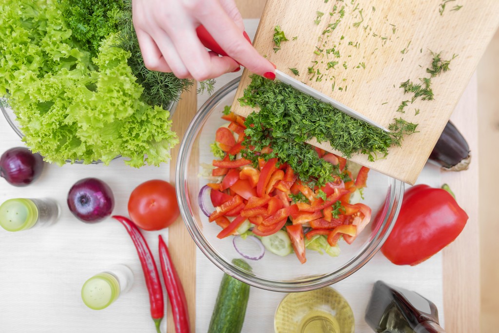 Women hands cut greens for a salad in the kitchen.
